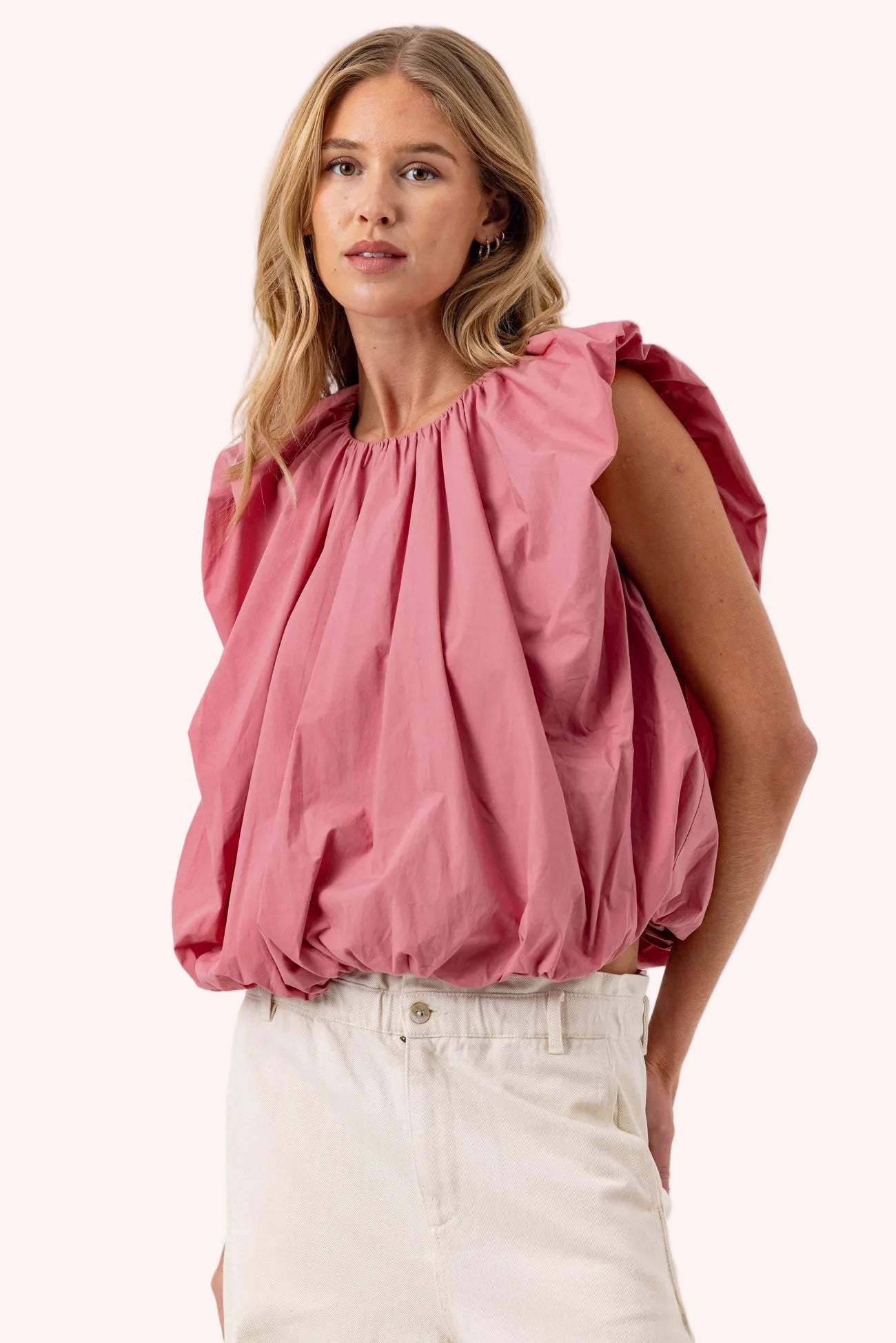 Woman wearing a pink blouse with balloon sleeves on a white background